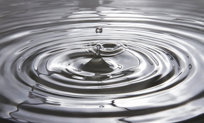 Water droplets falling against the surface of the water create a beautiful ripple on the gray water...