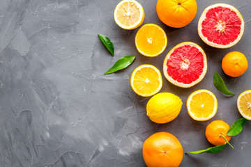 Citrus fruits frame - halfs of lemons, grapefruits, leaves - on grey background top-down copy space