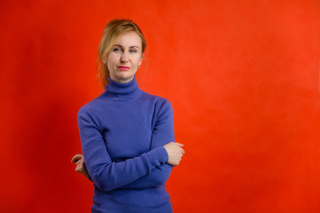 Portrait on a red background pretty woman blonde Caucasian 40 years old stands right in front of the camera