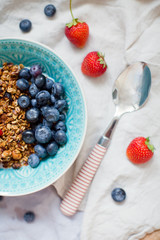 Bowl of homemade granola with yogurt and fresh strawberry and blueberry
