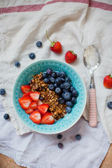 Bowl of homemade granola with yogurt and fresh strawberry and blueberry
