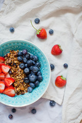 Bowl of homemade granola with yogurt and fresh strawberry and blueberry