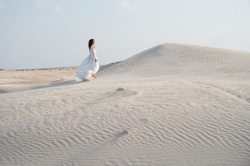 Bride walking in white wedding dress on sand dunes