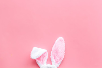 Easter bunny concept. Toy rabbit's ears on pink background top-down copy space