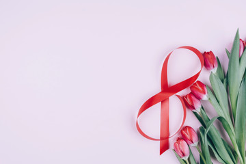Tulips and red ribbon on a pink background. Beautiful background for international women's day