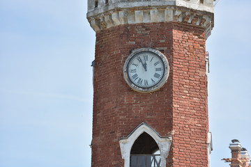 large and tall brick clock tower with blue sky background, with text space
