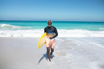 Old man with a surfboard at the beach
