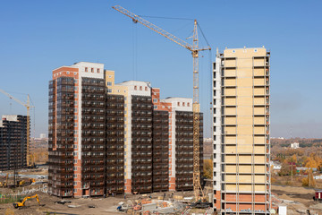 Construction of high-rise residential building. cranes working on building complex, with clear blue...