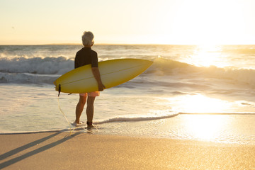 Old woman with a surfboard at the beach