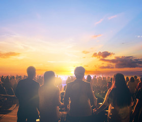silhouettes of concert crowd in front of sunset background