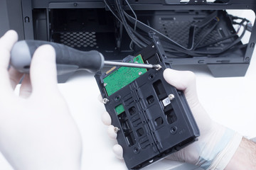 Technician assembling computer hardware parts. Hard drive being installed in a new computer