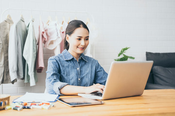 Fashion designer drawing new sketches collection and sent a business e-mail to client. satisfied...