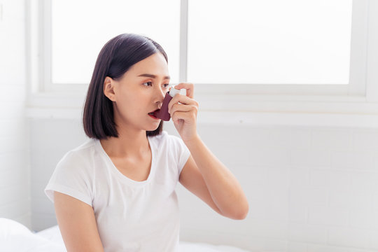 Asian Woman having asthma using the asthma inhaler for being healthy on her bed in bedroom