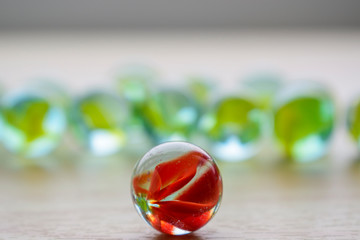 Glass ball with a red core on the plane. Background of yellow-green objects with highlights and blur. The concept of leadership, uniqueness, distinction.