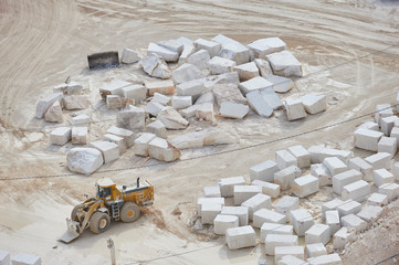 Mining industry: wheel bulldozer working in a marble quarry. Marble blocks