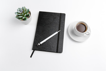 Notepad black closed and open with a pen with a Cup of coffee and a flower top view on a white background. Space for text