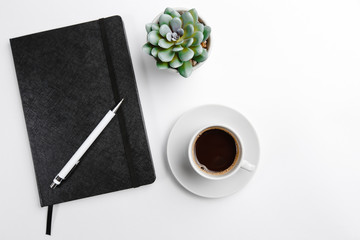 Notepad black closed and open with a pen with a Cup of coffee and a flower top view on a white background. Space for text