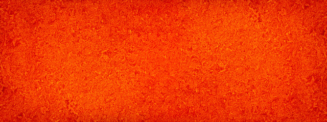 Red abstract background. Orange grunge background. Toned fiberboard texture. Bright colorful rough grainy surface. Close-up. Red grunge banner with copy space for your design.