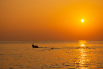 Fototapeta premium Black silhouette, beautiful sunset with a fishing boat, Mae Ramphueng Beach, Rayong Province, Thailand