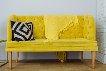 Beautiful yellow sofa with black and white pillows on a gray background