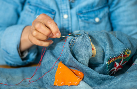 Elderly Woman Hands Sewing On Fabric Jeans , Needle.