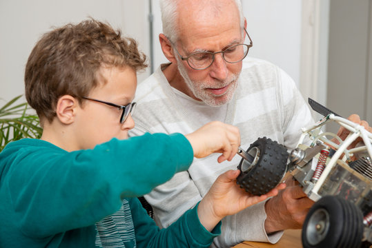grandpa and son little boy repairing  model radio-controlled car at home