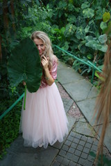  beautiful girl in a tropical garden with a huge green leaf