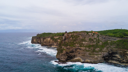 Aerial view of sea rocky coast with surf the waves, Bali, Indonesia, Pura Uluwatu cliff. Waves crushing rocky shore. Seascape, rocks, ocean. Travel concept.