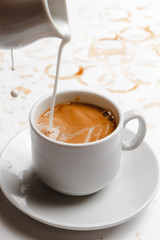 cream is poured into black coffee on a white background filled with coffee. a place for a label