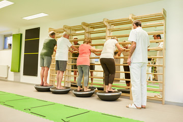 Gruppe Senioren trainiert Balance auf einem Bosu Ball