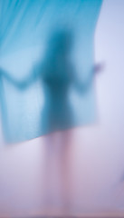 Blurred photo girl with cloth dancing behind glass