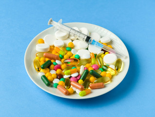 Pills, tablets, syringe, vitamins, drugs, medicine in a white dish for medical treatment. Blue...