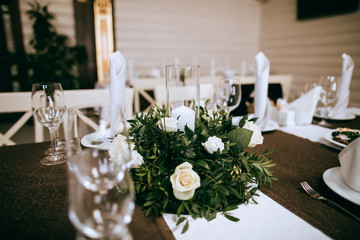 Wedding reception table decoration.  White roses and candles on dinner table.