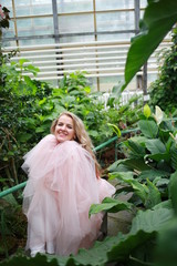  beautiful white long hair girl in a tropical garden in a light tulle pink skirt