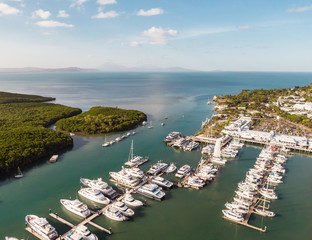 Marina town with waterfront river view of yachts and boats in sea water. Carins Port Douglas aerial view. Dramatic DRONE view from above. Mountain landscape in background. Queenstown, Australia. © Jam Travels