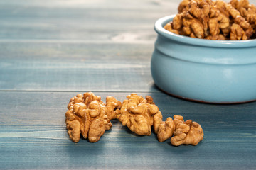 Walnuts in a blue cup on a blue wooden table.