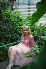  beautiful white long hair girl in a tropical garden in a light tulle pink skirt