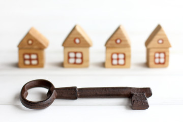 Big iron key on a background of blurry silhouettes of wooden houses. complete solutions for individual real estate