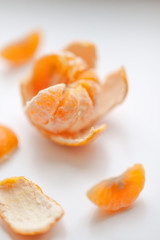 ripe mandarin with slices and peel on a white table.