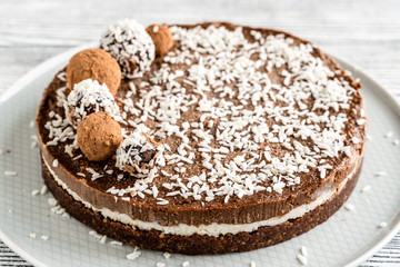 chocolate cake on a plate. Chocolate and coconut cake on a white wooden background. Foodfoto in a high key. Raw dessert
