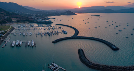 Sunset Panoramic marina town aerial. Airlie beach waterfront aerial view. Dramatic DRONE view from above. Marina town with yachts and boats in sea water. Mountain landscape. Whitsundays Islands