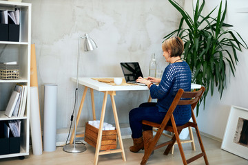 Attractive businesswoman sitting in modern office and typing.