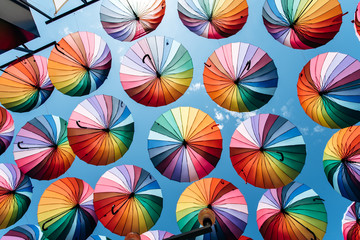 Fototapeta na wymiar Umbrellas in rainbow color on blue sky background