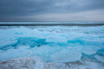 Fototapeta na wymiar Field of ice hummocks on the frozen lake. Cracked ice on lake in winter season, natural landscape background.