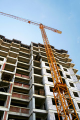 Naklejka premium Tower crane near building. Construction site. High-rise multi-storey building under construction.