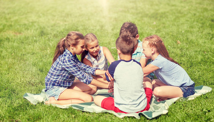 Fototapeta premium summer holidays, friendship, childhood, leisure and people concept - group of happy pre-teen kids putting hands together in park