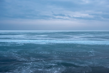 Fototapeta na wymiar Field of ice hummocks on the frozen lake. Cracked ice on lake in winter season, natural landscape background.