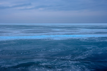 Field of ice hummocks on the frozen lake. Cracked ice on lake in winter season, natural landscape background.
