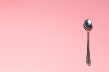 On a pink background is a teaspoon. Close-up. Concept: breakfast, farm