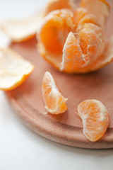 Fototapeta na wymiar Ripe orange mandarin with slices and peel on a wooden board. Soft blurred focus.